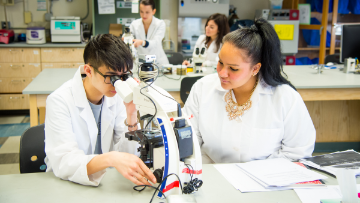 Student looks into microscope.