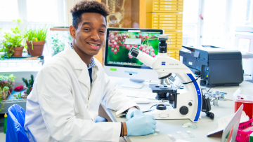 Student smiles while using microscope.  