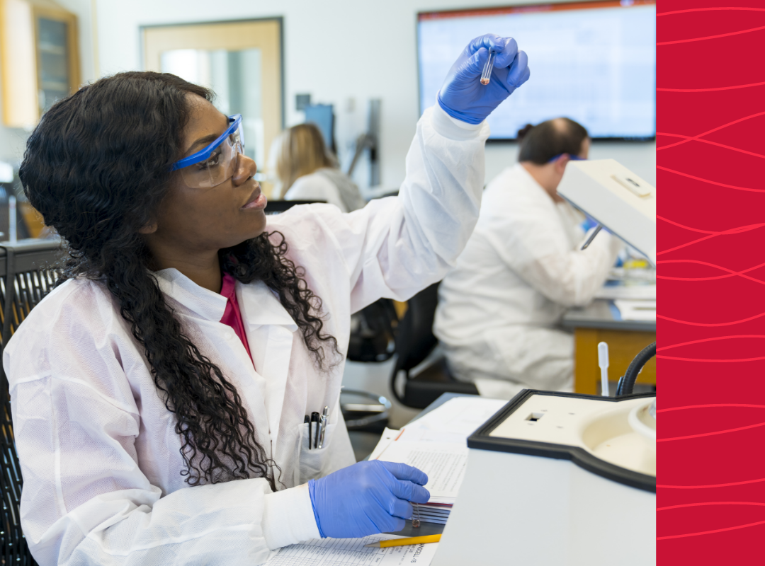 A student in a lab looking at a test tube.