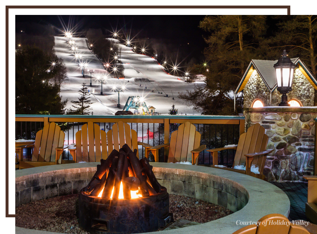 A fire pit at Holiday Valley ski resort, with the snow-covered slopes in the background