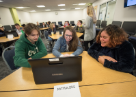 Three students work on laptop. 